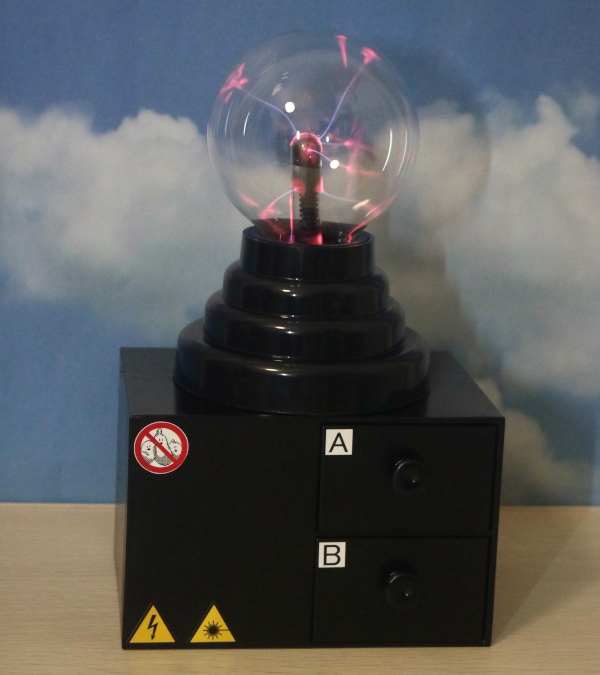仮想物質装置の全体像（AとBのラベルが貼られた2つ引き出しを備えた黒い台と、その上に設置されたプラズマを放つ球体）